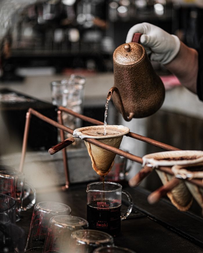 Close-up of artisan coffee brewing using a pour over method with kettle and ceramic dripper.