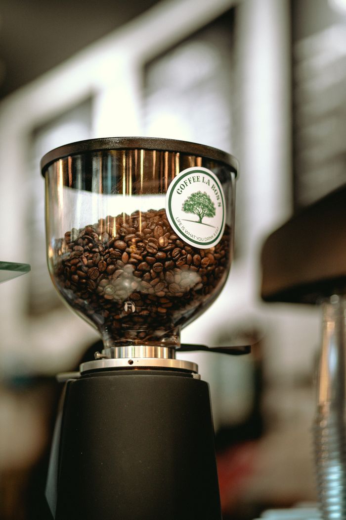 Close-up of a coffee grinder with beans in a Baku café setting.