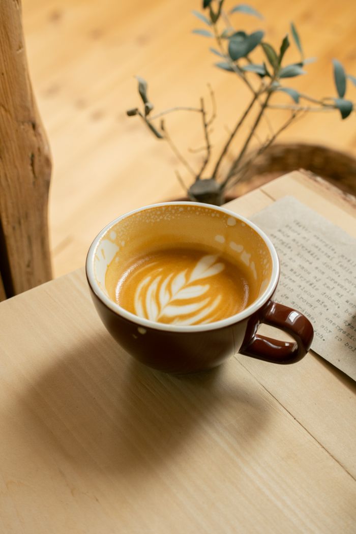 Warm, inviting cafe setting with latte art coffee in Sabinov. Perfect for coffee enthusiasts.