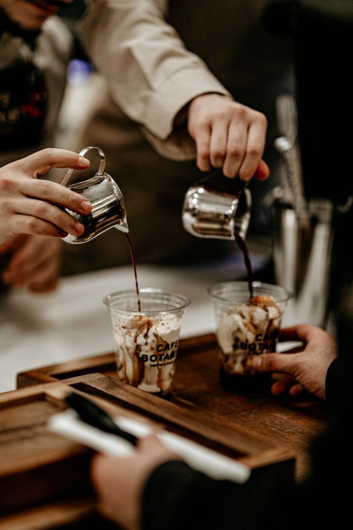 Close-up of baristas pouring coffee into cups at a cafe counter.